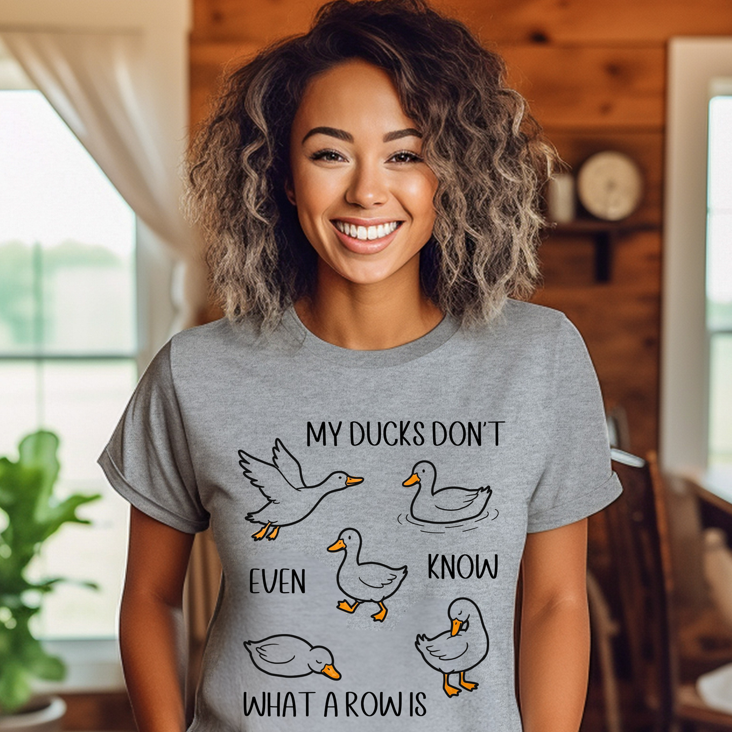 Woman wearing a gray t-shirt with duck graphics and text in a home setting