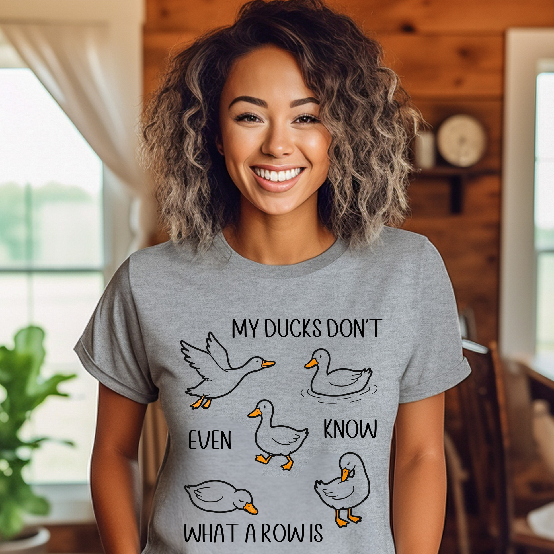 Woman wearing a gray t-shirt with duck graphics and text in a home setting