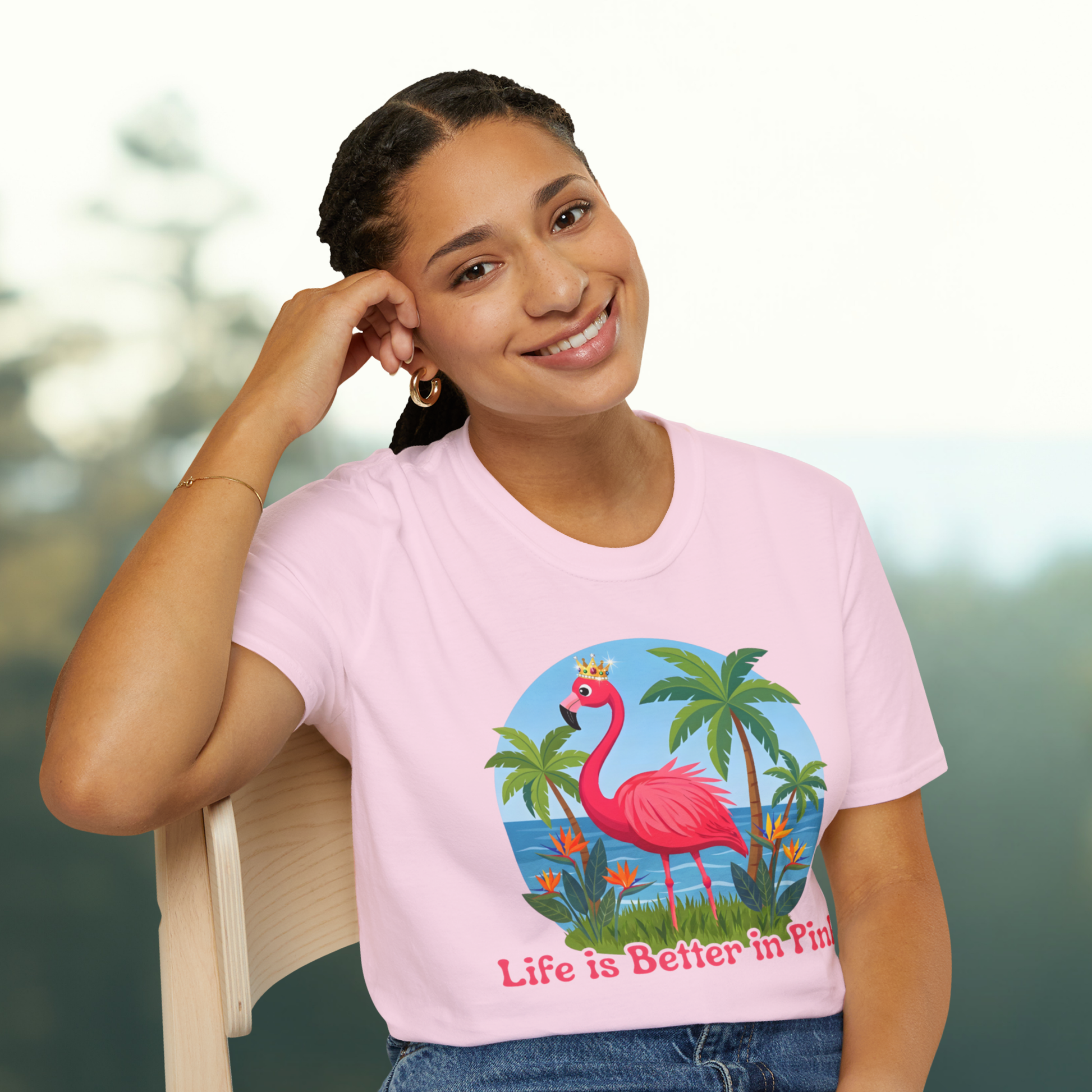 Woman wearing a pink t-shirt with a flamingo graphic and text, sitting outdoors.