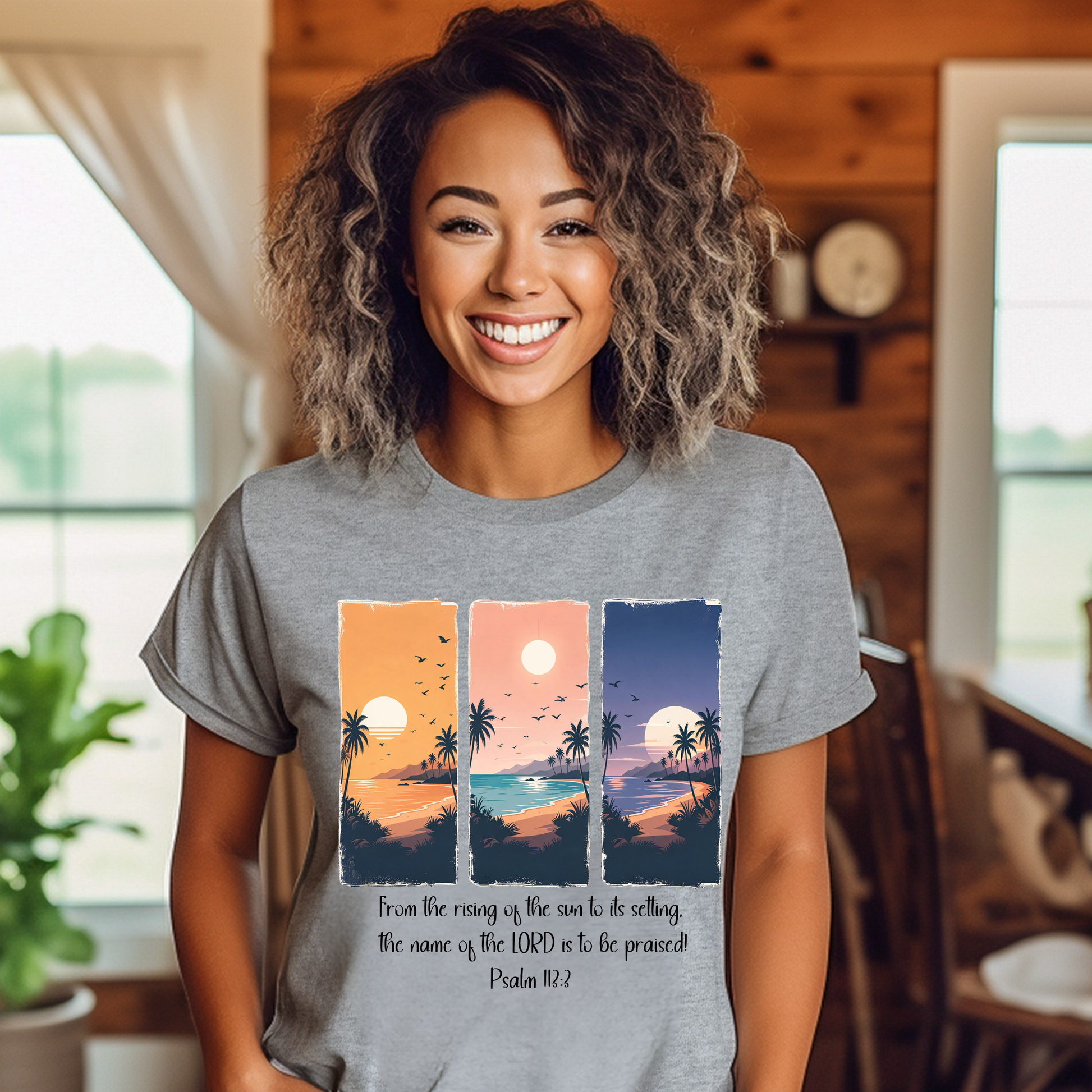 Woman wearing a gray t-shirt with sunset design and text in a home setting