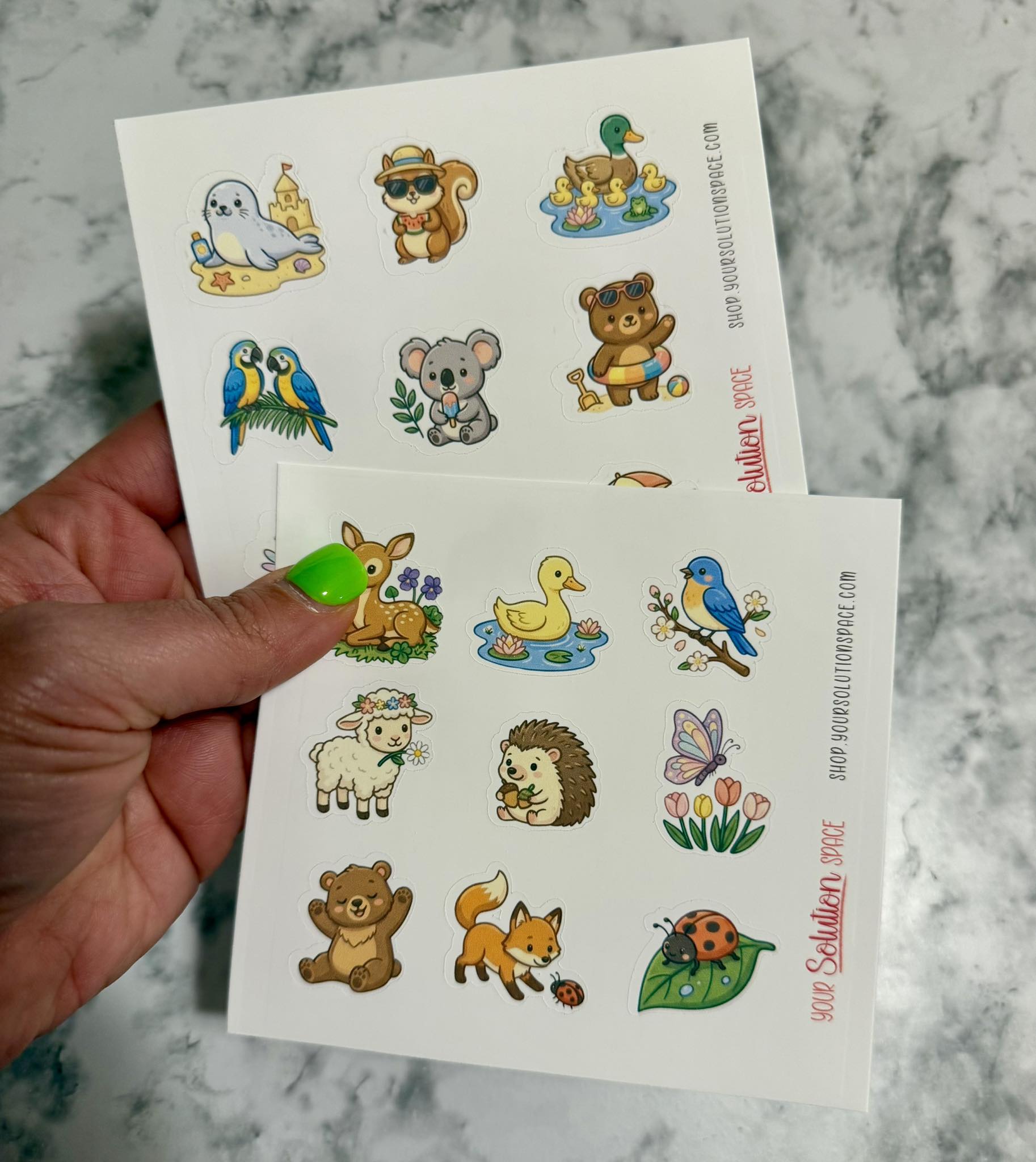 Sheet of animal stickers held by a hand on a marble surface