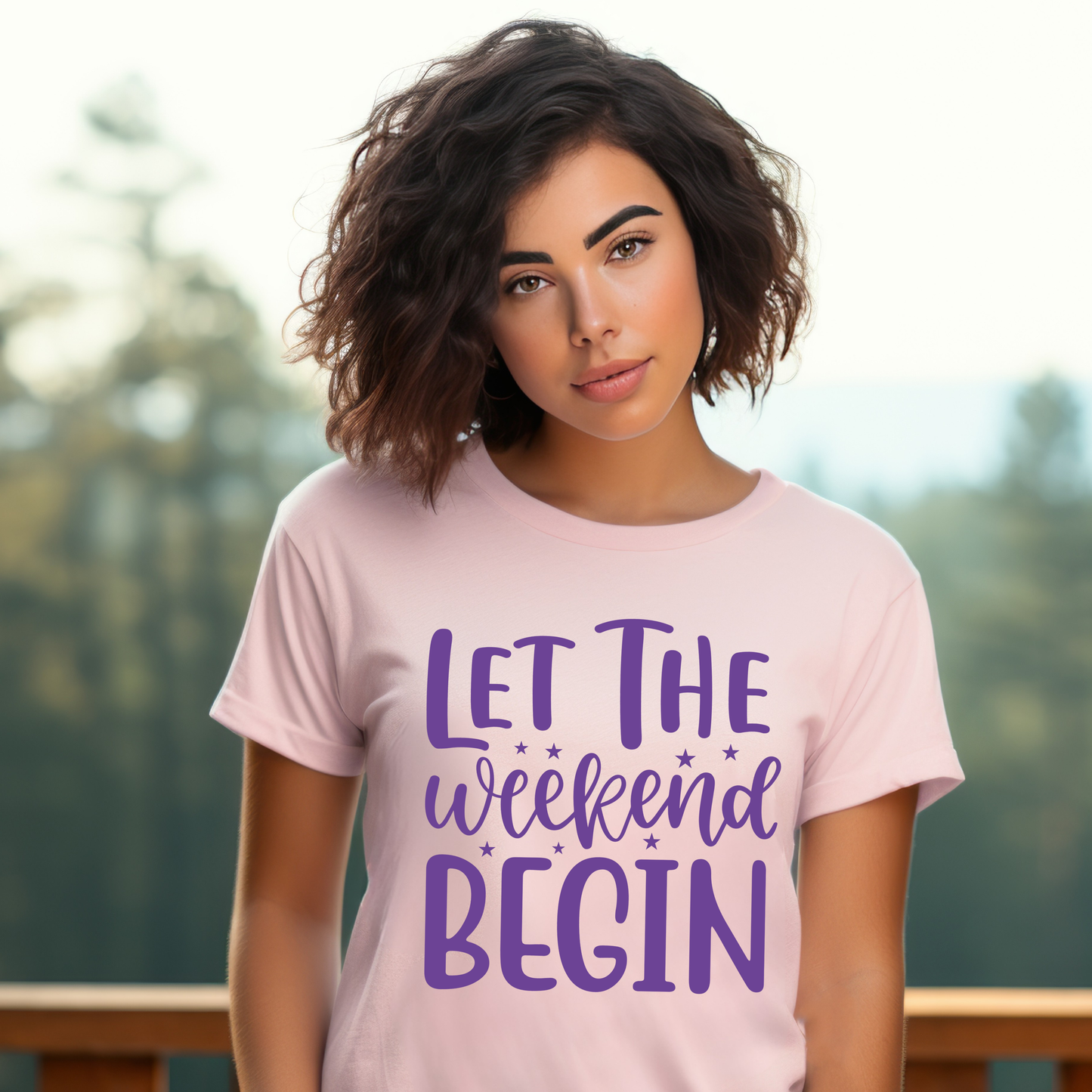 Woman wearing a pink t-shirt with 'Let the weekend begin' text in purple outdoors.
